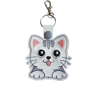 White faux leather kitty cat keyring with embroidered grey details, pink ears and tongue, black eyes, and a silver split ring with lobster clasp.