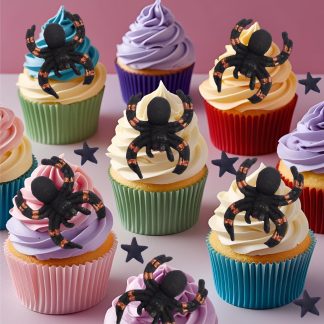 6 large spiders on top of creamed cupcakes in a party setting
